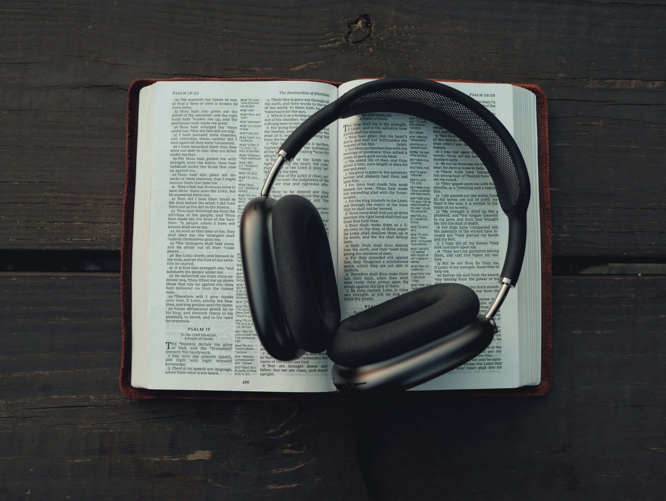 Bible ouverte avec un casque audio posé dessus, symbole de méditation spirituelle et écoute de la Parole.