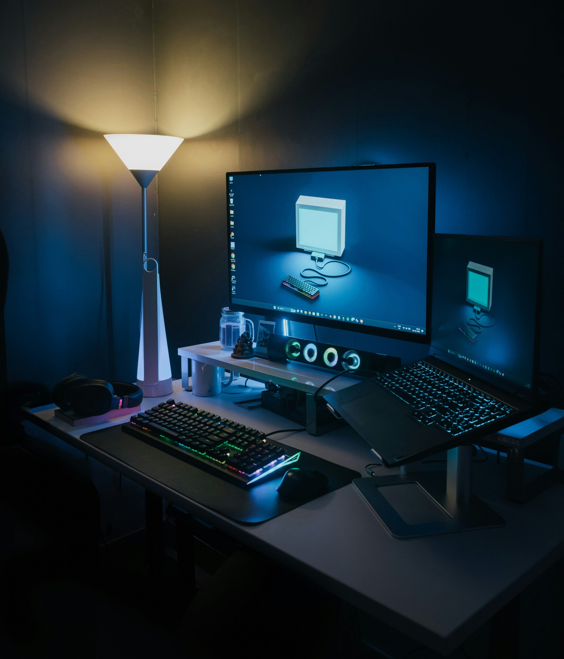 Configuration d’un bureau multimédia sombre avec ordinateur, écrans et ambiance lumineuse tamisée.